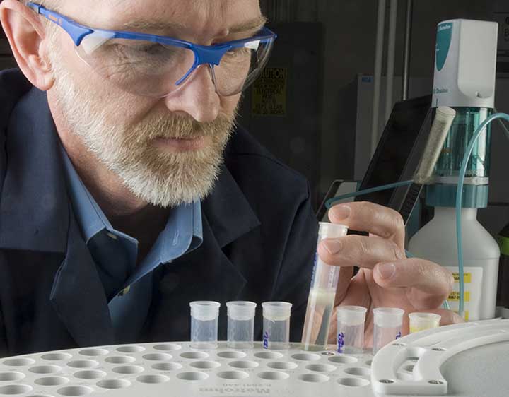 A man wearing goggles examines a biodiesel sample in NREL's Fuel Chemistry Laboratory.