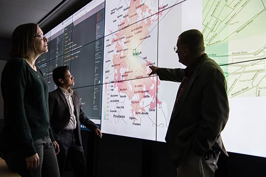 Photo of three people looking at a large map.