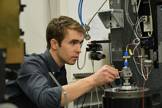 A man works on equipment in a lab.