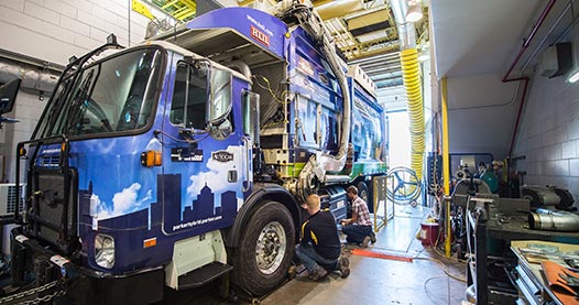 A hybrid garbage truck undergoing testing in a lab.