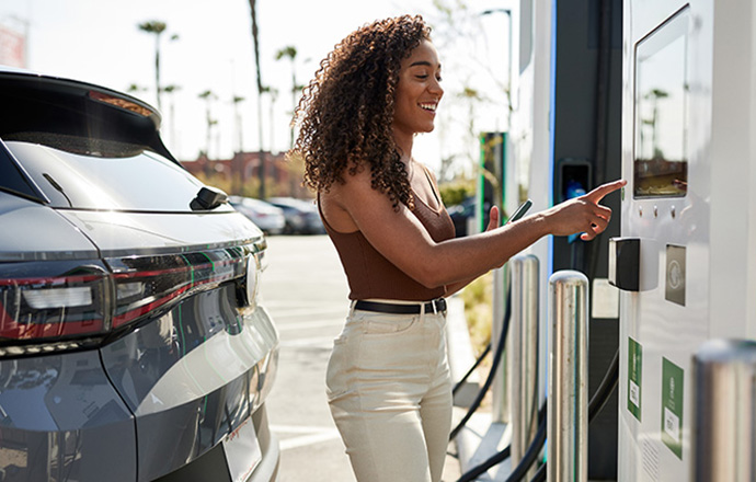 A woman paying at an electric car charging station.