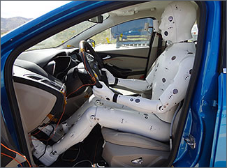 Image of a model human body in the driver's seat of a car.