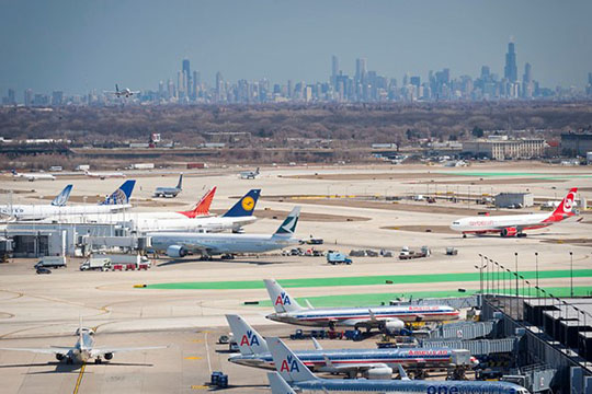 An airport tarmac with city skyline in the background.