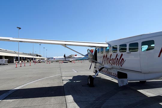 A Mokulele airplane sits on the tarmac at a small airport.