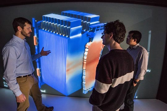 Researchers gathered around a computer model of a Li-ion battery.
