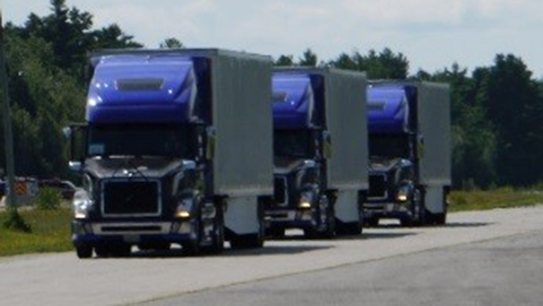 Three semi trucks platooning on a highway