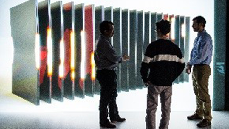 NREL energy storage researchers evaluate simulation stills of a battery in the ESIF 3-D visualization room