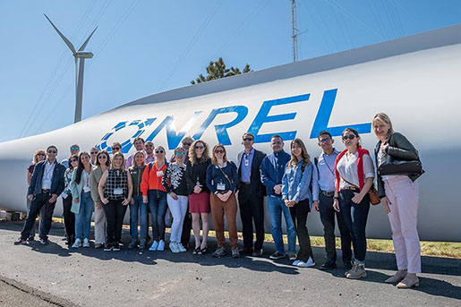 The cohort of young Colombian Energy Leaders stand in front of a wind turbine blade at the NREL Flatirons campus.