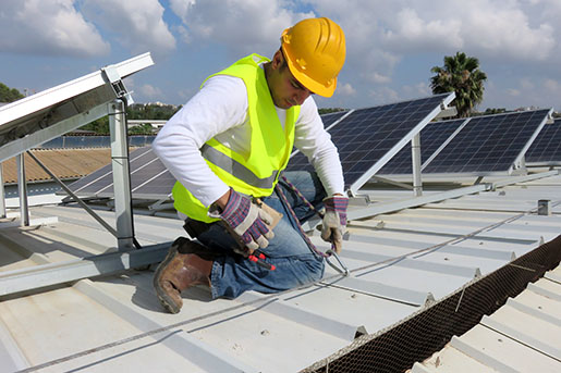 A worker crouches next to a solar PV installation