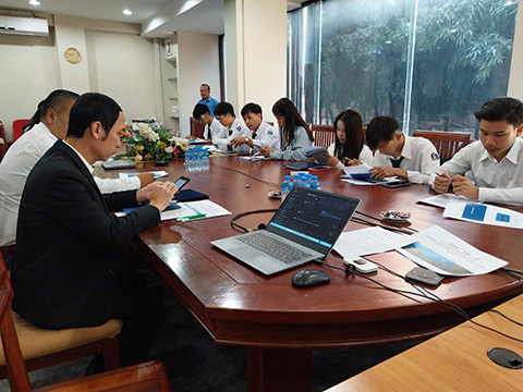 Several partners from the Ministry of Energy and Mines in Laos are gathered around a conference table with laptops and notebooks out, working on using the OpenPATH tool.