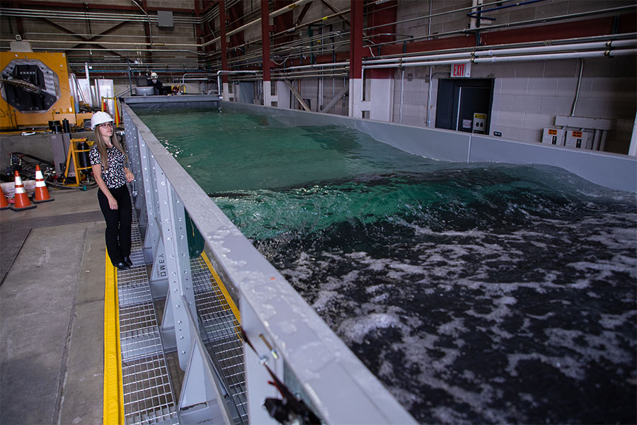 Person stands to the side of wave tank inside laboratory.