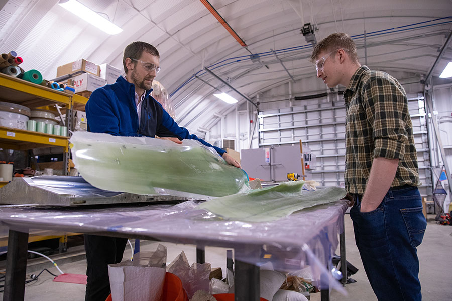 Two researchers examine 3D printed turbine blade.