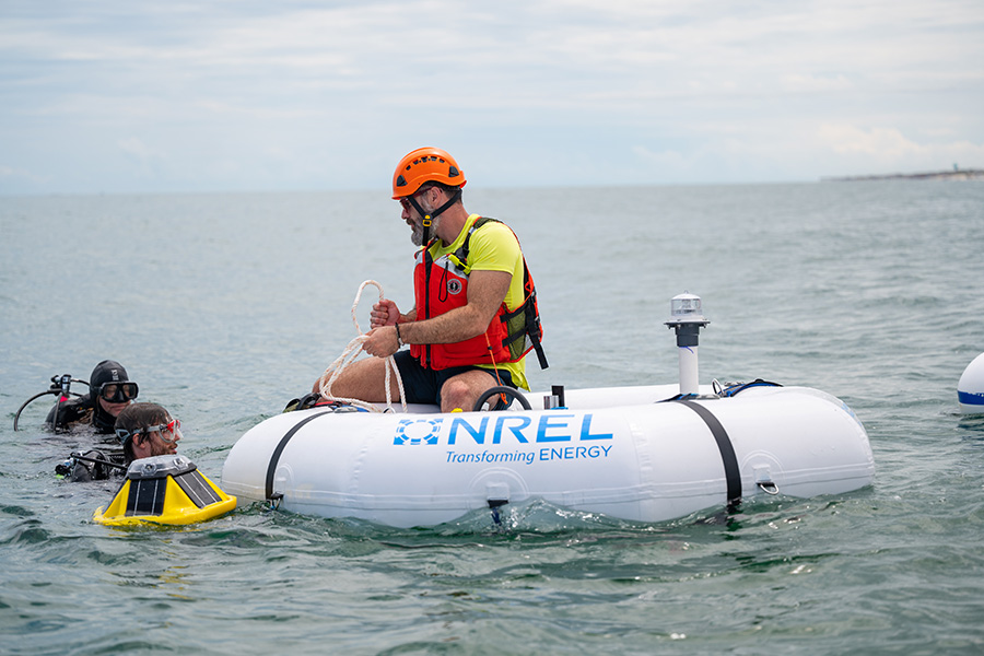 A team of divers prepare a wave energy converter device in the ocean.