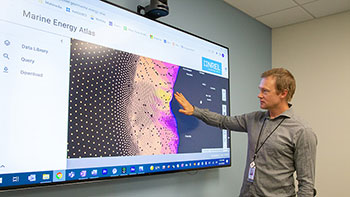 Researcher presenting data from the Marine Energy Atlas on a large monitor.