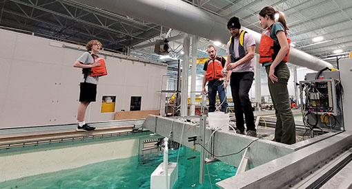 A group of students standing around a wave simulator