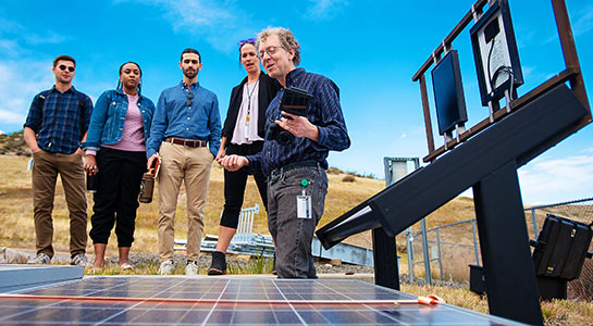 A group of people standing behind a solar panel