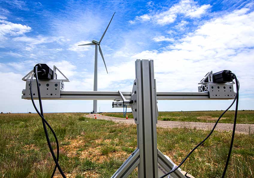 The ThermalTracker device sits in the foreground of a wind turbine.