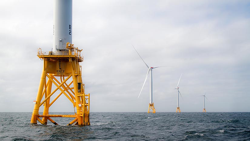 Photo of a row of wind turbines installed in the ocean.
