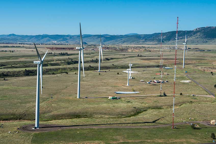 An aerial photograph of NREL’s Flatirons Campus with wind turbines and meteorological towers on a clear sky day.