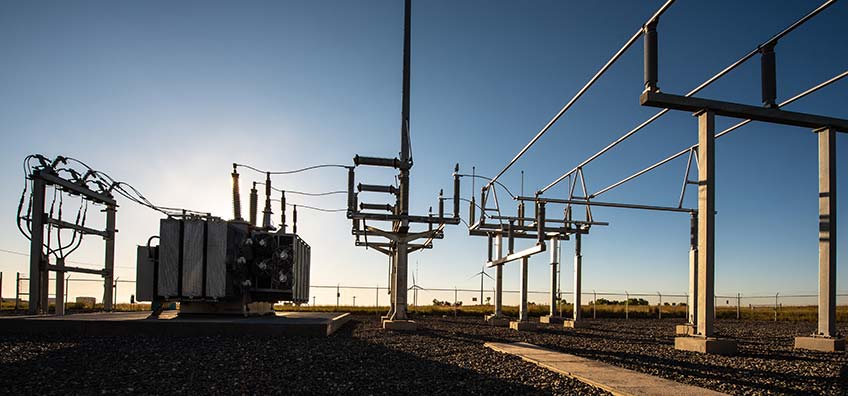 A low-angle photograph of the shadow of a substation with the sun blocked by a transformer.
