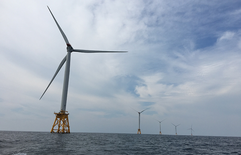 Several large offshore wind turbines standing in a line.