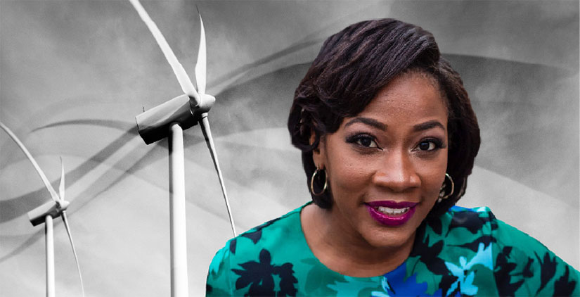 A headshot of Angel McCoy in front of two wind turbines