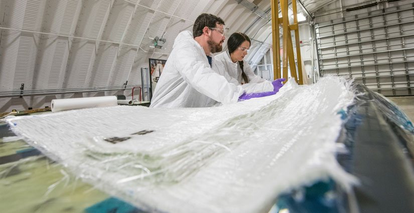 NREL researchers Robynne Murray and David Barnes laying up a turbine blade in a blade mold at the CoMET at Flatirons Campus.