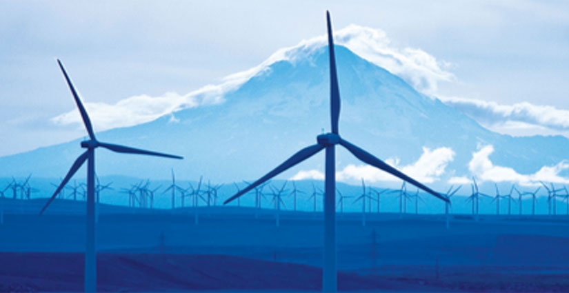 Wind turbines in front of snowy mountain.
