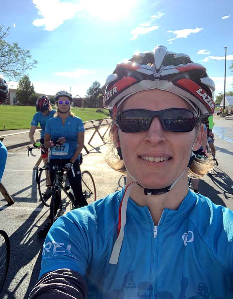 Aubryn in a helmet and sunglasses with a group of bicyclists