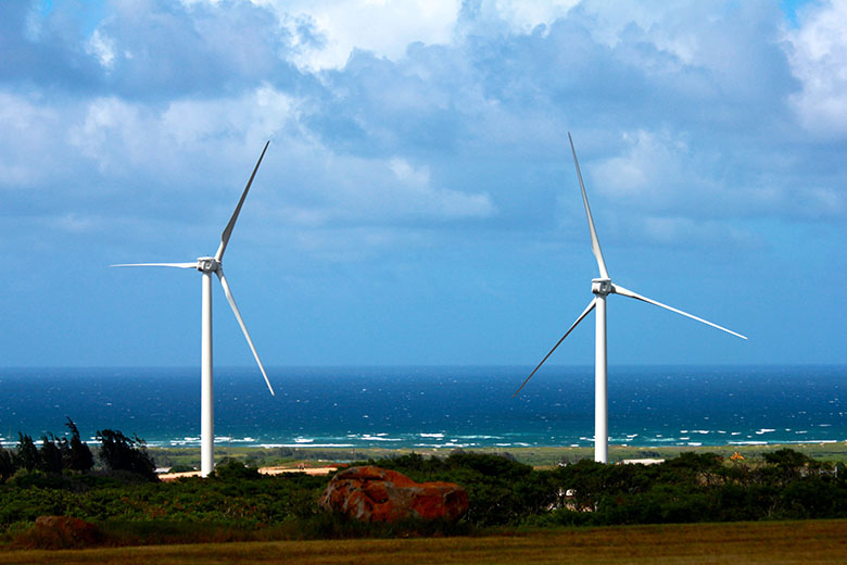 Two wind turbines on a beach.