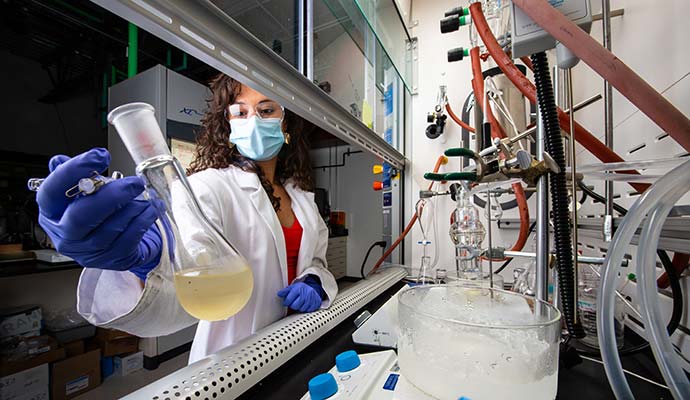 Scientist in NREL laboratory holding beaker.