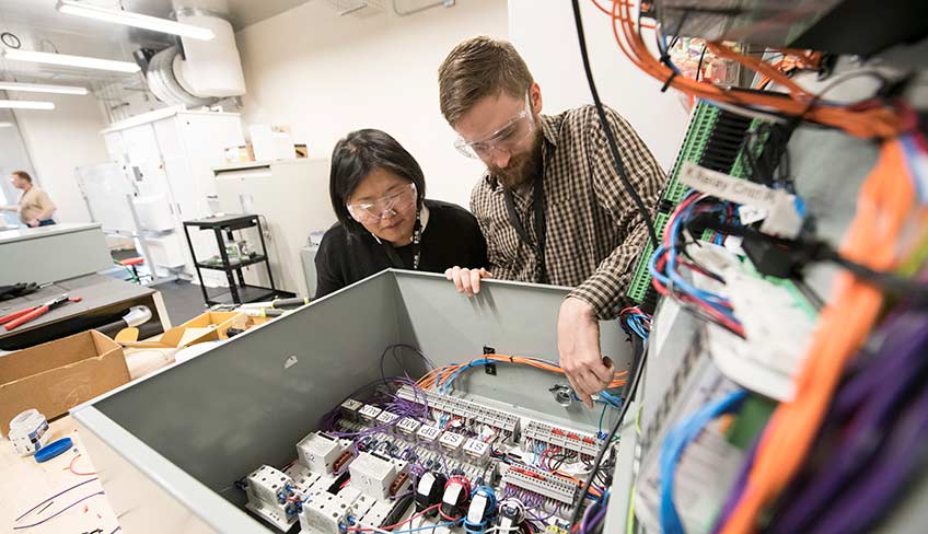 A woman and man look at a hardware prototype in a laboratory.