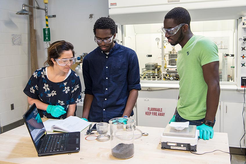 Researchers and JUMP into STEM intern examine graphite pucks in an ESIF lab.