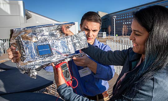 Participants in NREL's Mini-Semester for Undergraduate Students construct mini-solar concentrators to see how much power they can get from a solar cell.