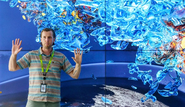 Researcher presenting in front of a wall-sized 3D data visualization
