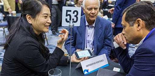 iec-69704 Three people talk while seated at a table.