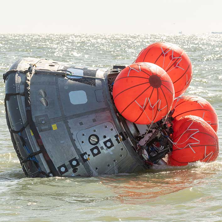 A spacecraft undergoing tests In the ocean. The ship is partially submerged.