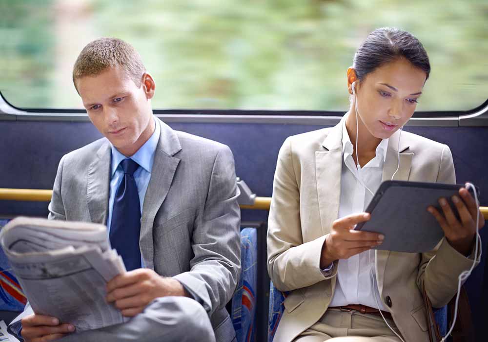 Two business people reading catching up on the news on their commute to work