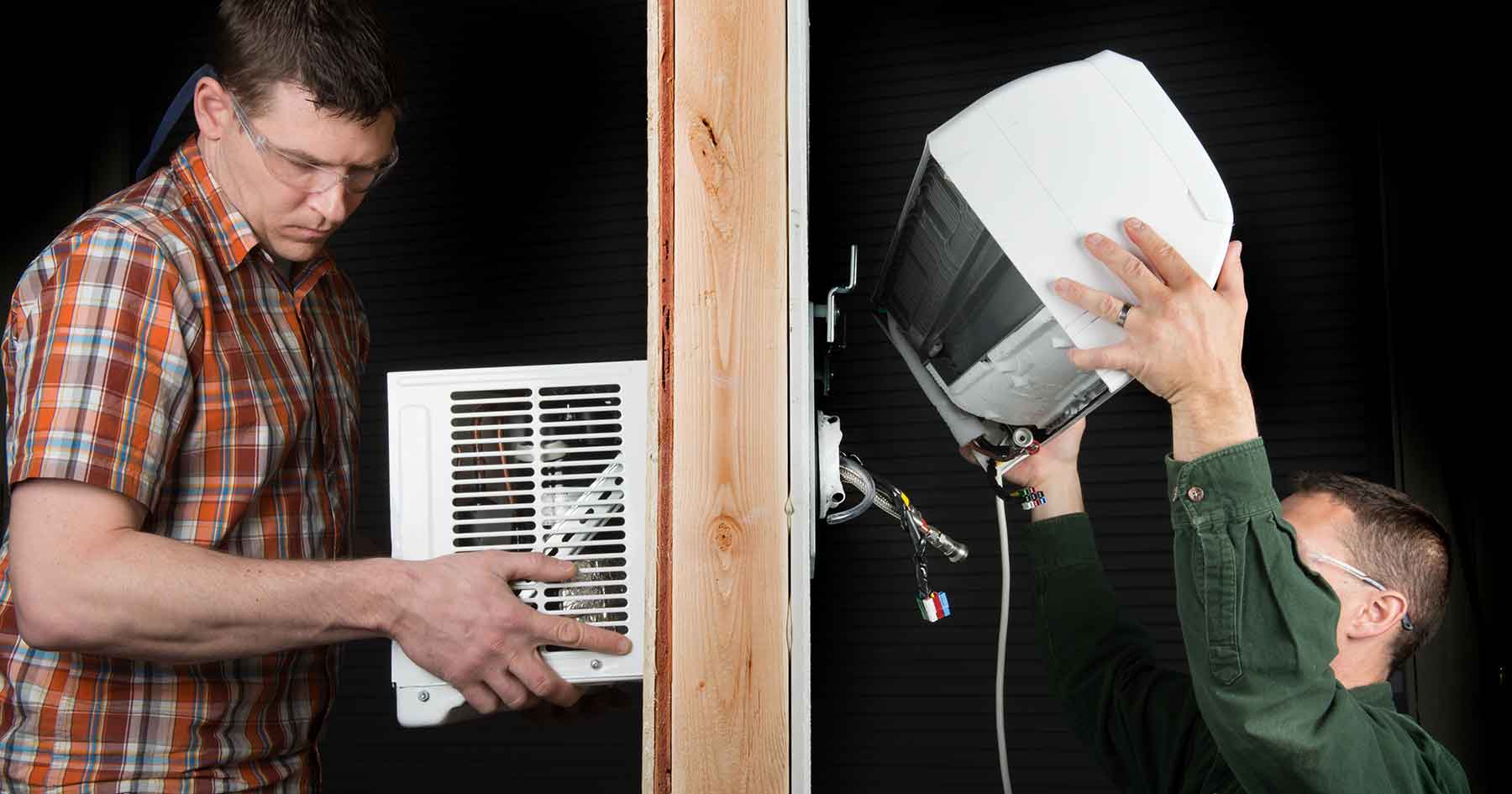 Two men shown on opposite sides of a wall installing the EcoSnap-AC Heat Pump System