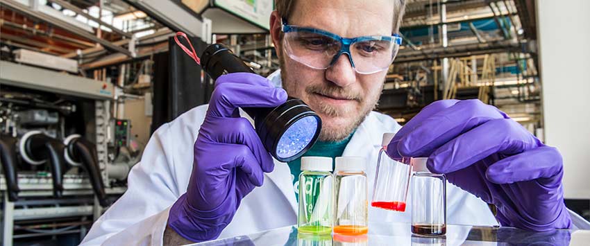Christians works with vials of brightly colored perovskite quantum dot solutions at the National Renewable Energy Laboratory.