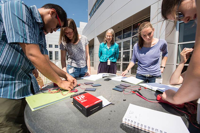 A researcher works with college students as they build solar cell concentrators.