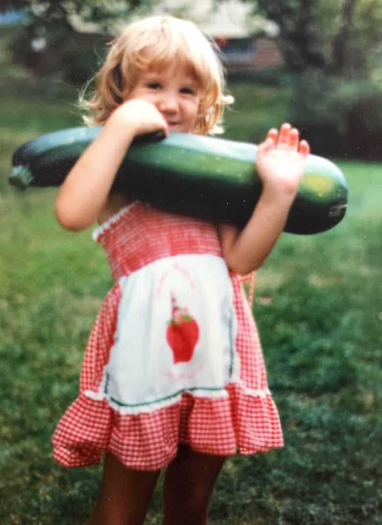 A child holding a very large zucchini 