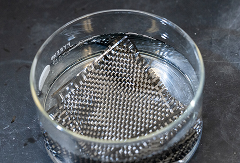 a carbon fiber composite in a clear dish with liquid.