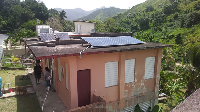 An image of a home in Jayuya, Puerto Rico with rooftop solar power in the mountainous region with palm trees